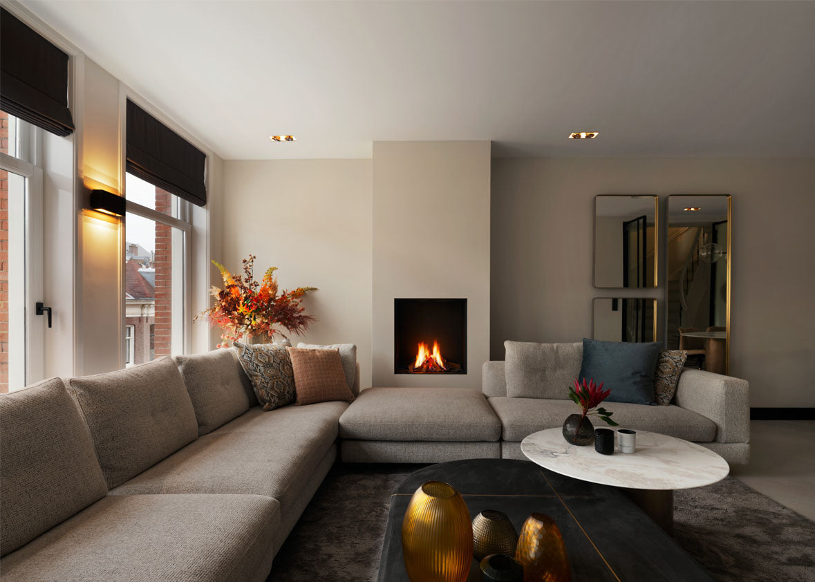 Living room with fireplace, wall sconces and recessed spotlights above corner sofa