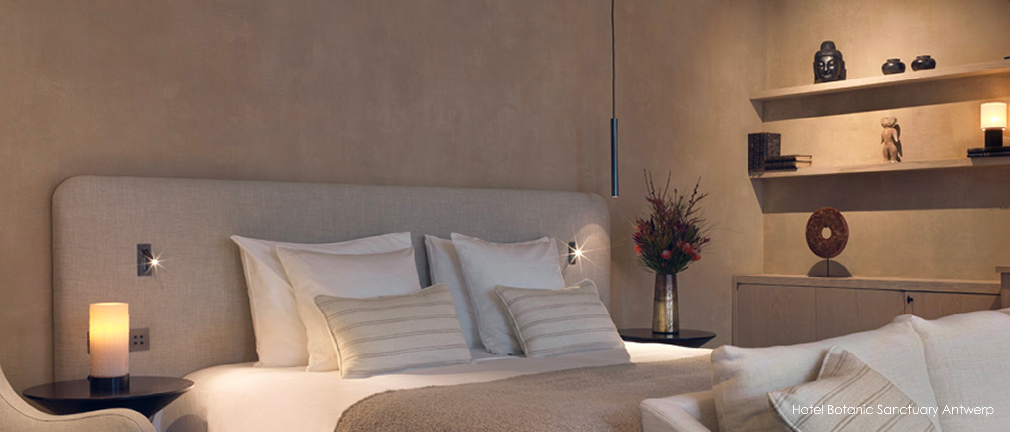 Elegante hotelsuite met royaal bed, zachte stoffen en minimalistische hanglamp.